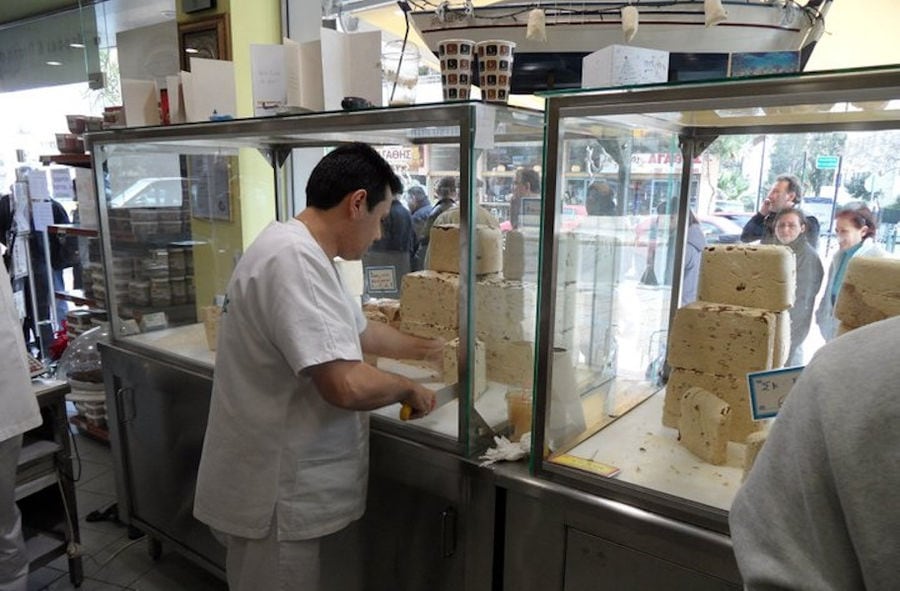 man cutting Greek 'halva' with a knife at 'M. Kosmidis' store